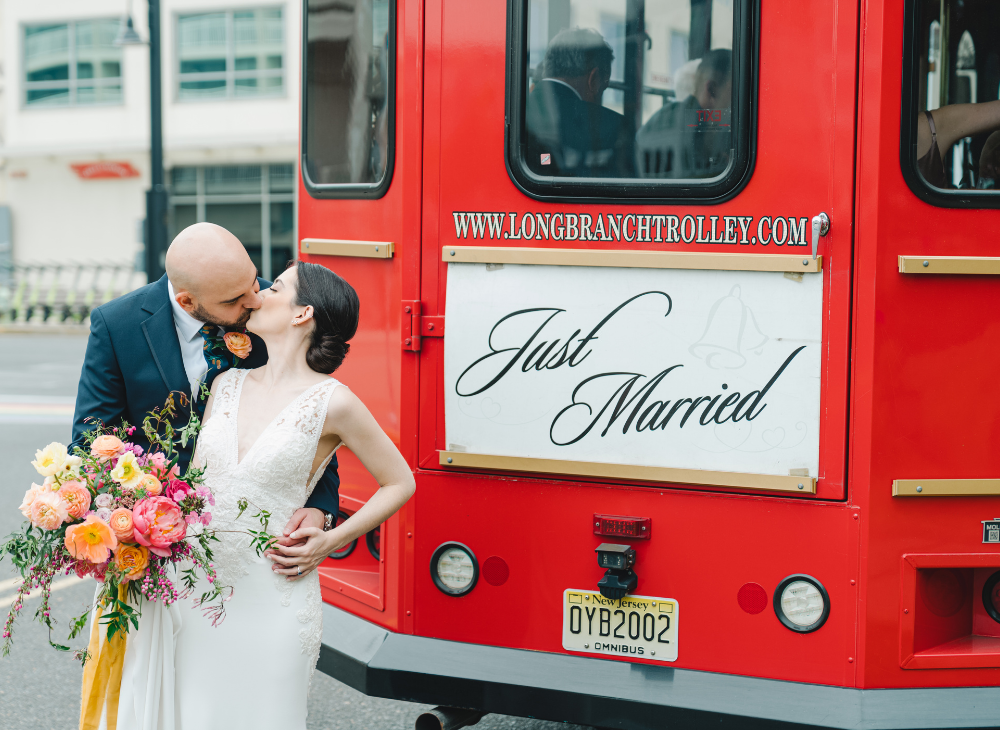 bride and groom kiss in front of just married long branch trolley
