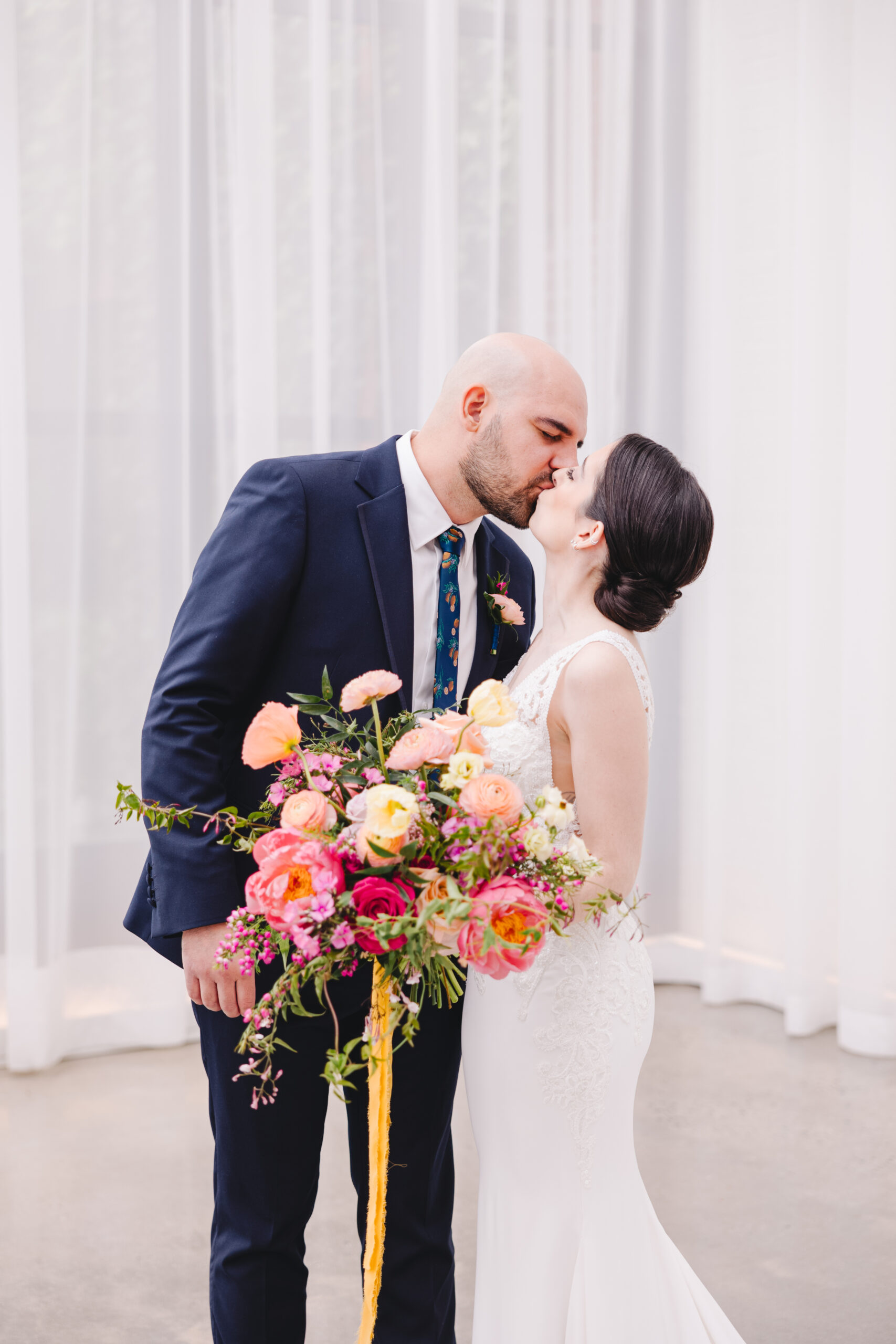 bride and groom kiss with pink bouquet