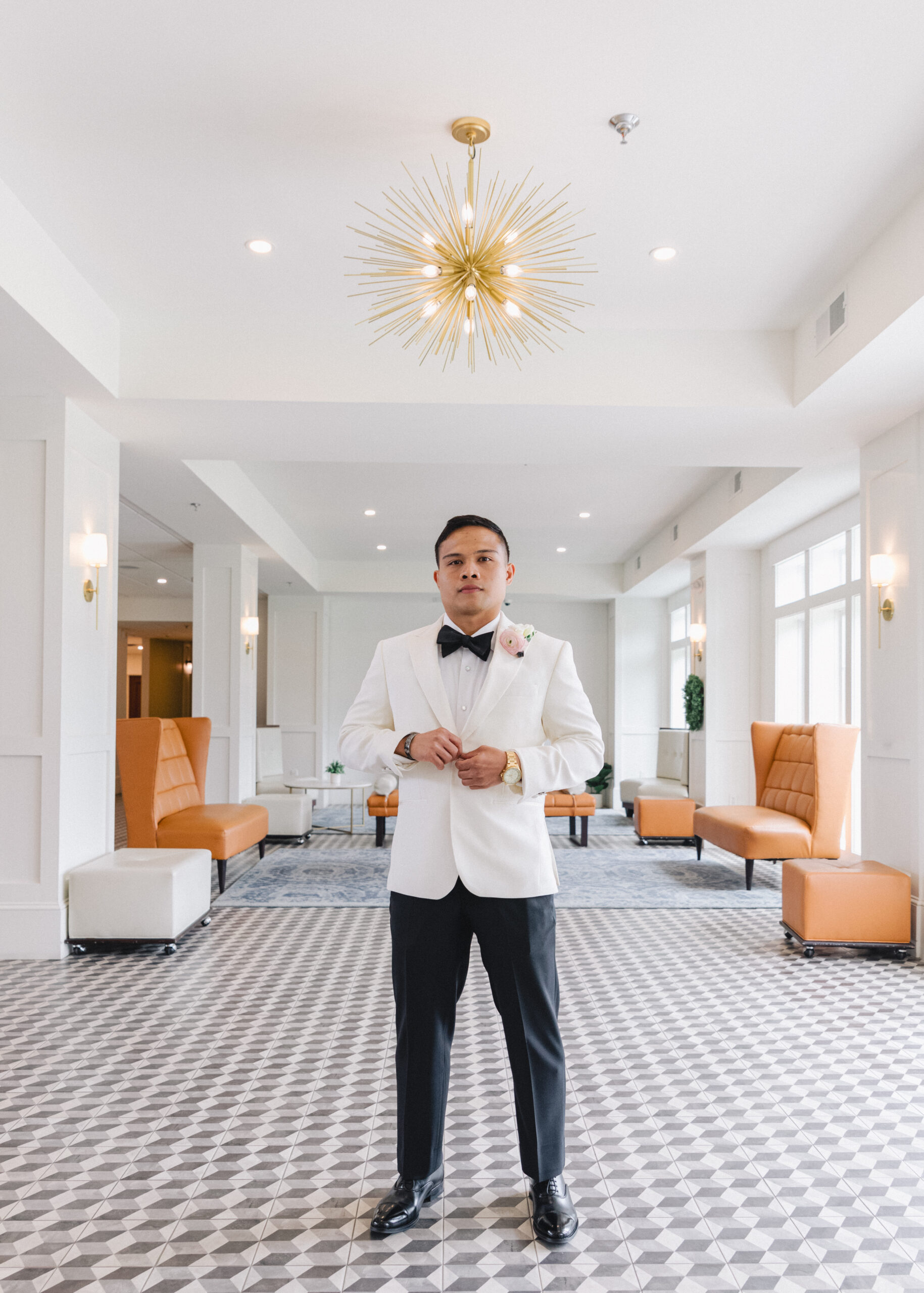 groom buttoning jacket in modern hotel foyer