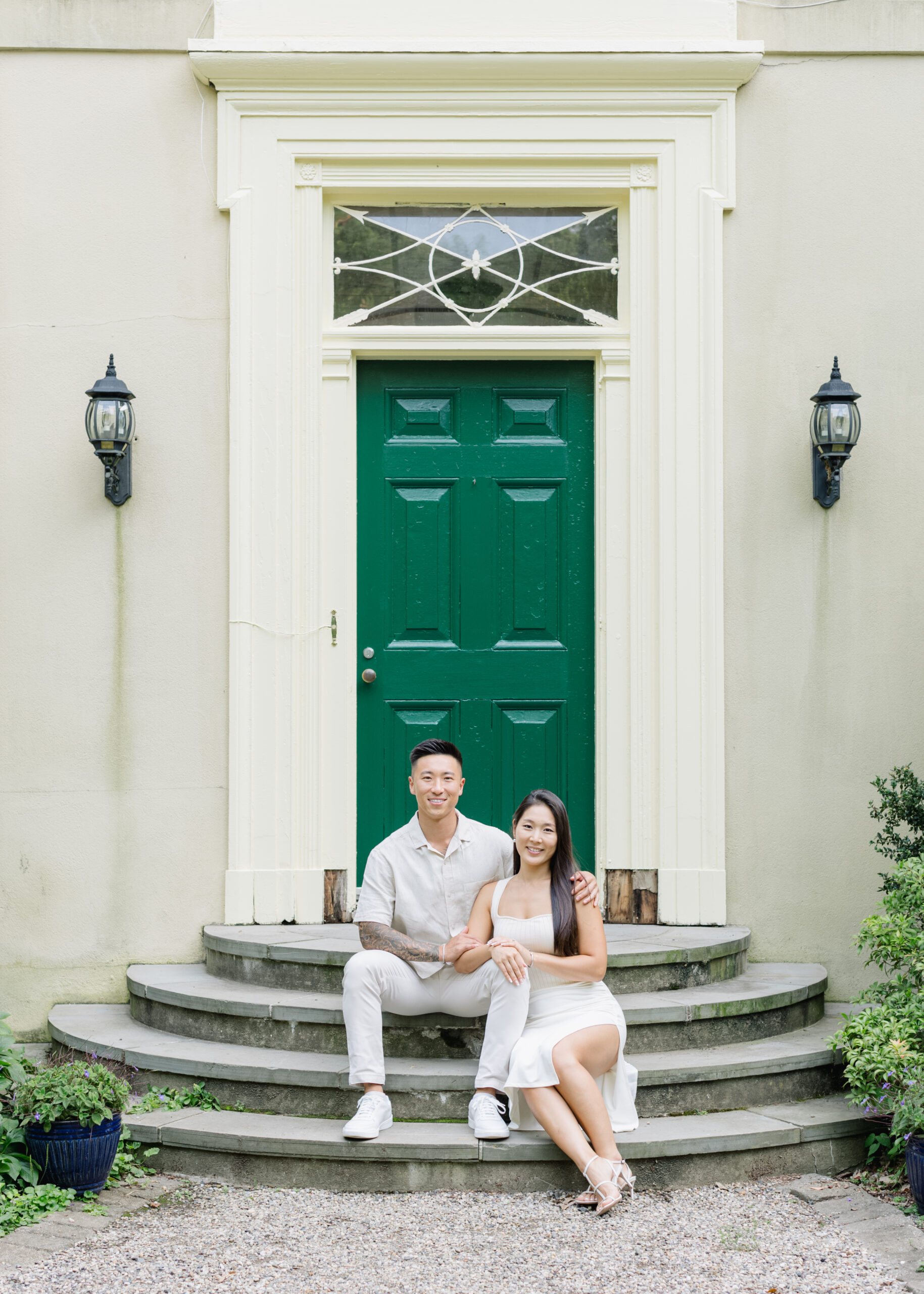engaged couple sitting on steps with green door at cross estate gardens
