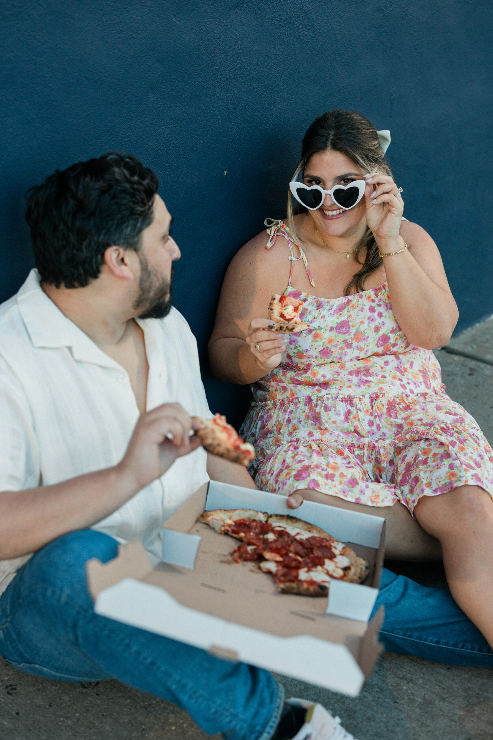 couple with pizza at Porta for engagement photos holding sunglasses